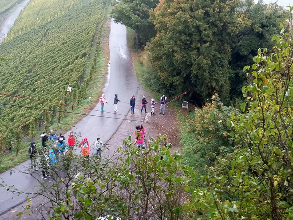 Blick von der Seilrutsche auf die Gruppe am Zielpunkt.